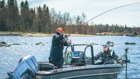 Män som fiskar från en båt med Honda BF30-motor i sjöområde.