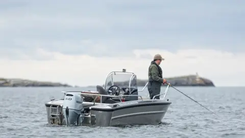 Man som fiskar på en båt med Honda BF60-motor.
